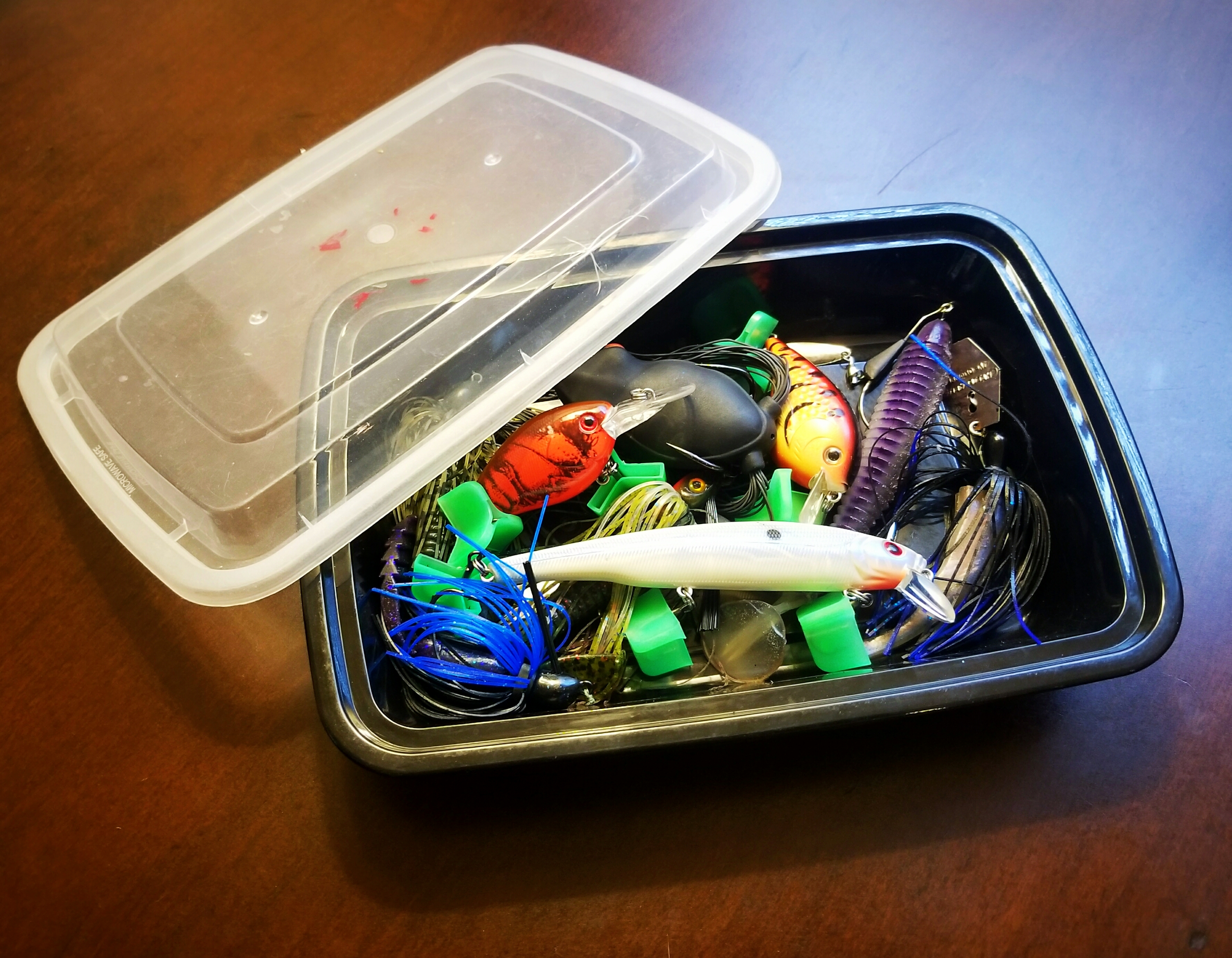 Recycled plastic takeout food container full of wet fishing lures