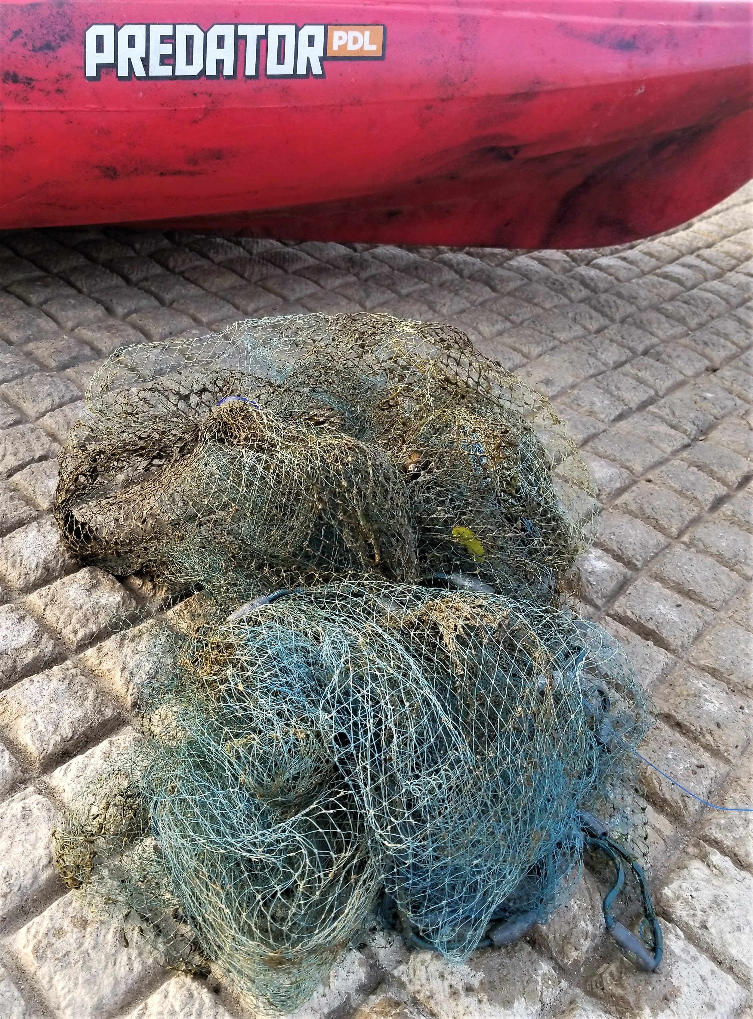 A tangled fishing net Katie pulled out of the lake laying on the boat ramp next to her kayak
