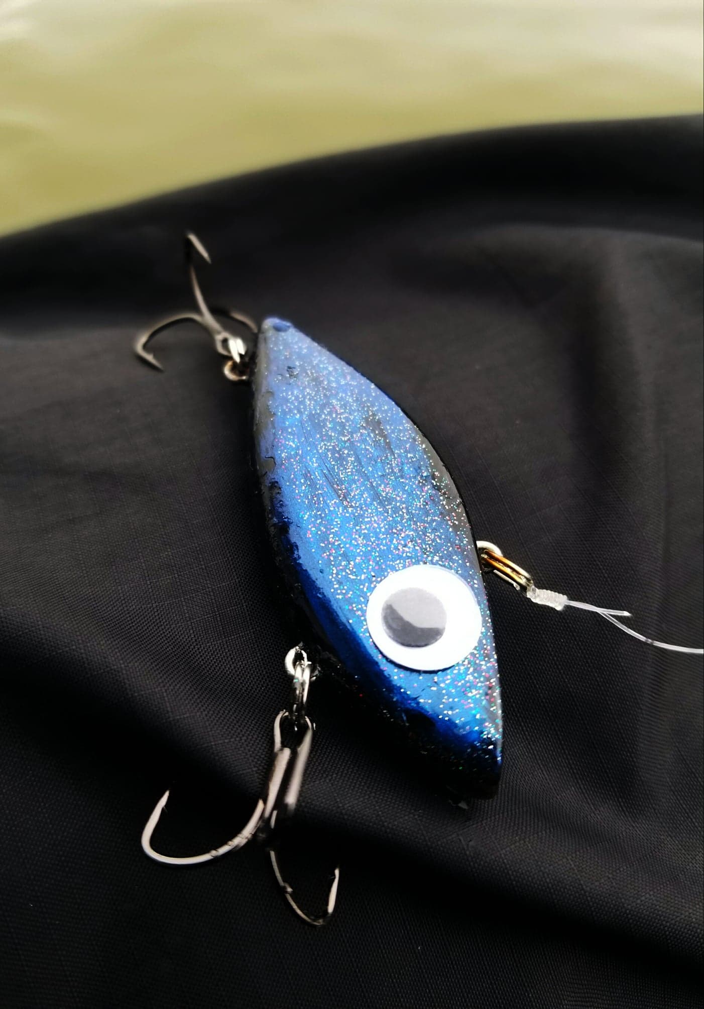 Black and blue painted Rattle Trap lure with glitter clear coat and googly eyes tied onto a fishing line